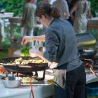 Chefkoch würzt Gemüse im Wok, Gartenfest für Kunden