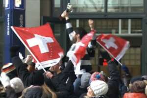 People at railstation bear supporter of Swiss Olympic Team on shoulders