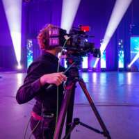 Studio in blue and purple light with cameraman capture video material for livestream